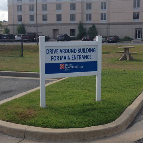 Decorative hotel property sign installed in an ornamental frame system.