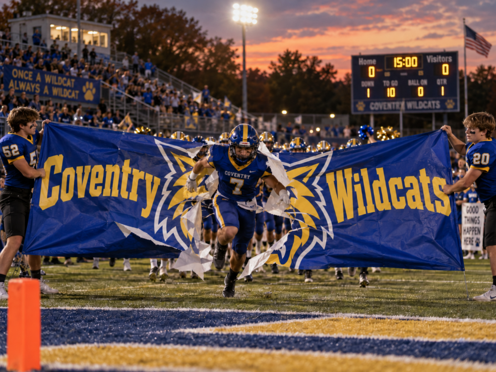 Football player breaking through a custom blue and gold school sports banner at a fall game